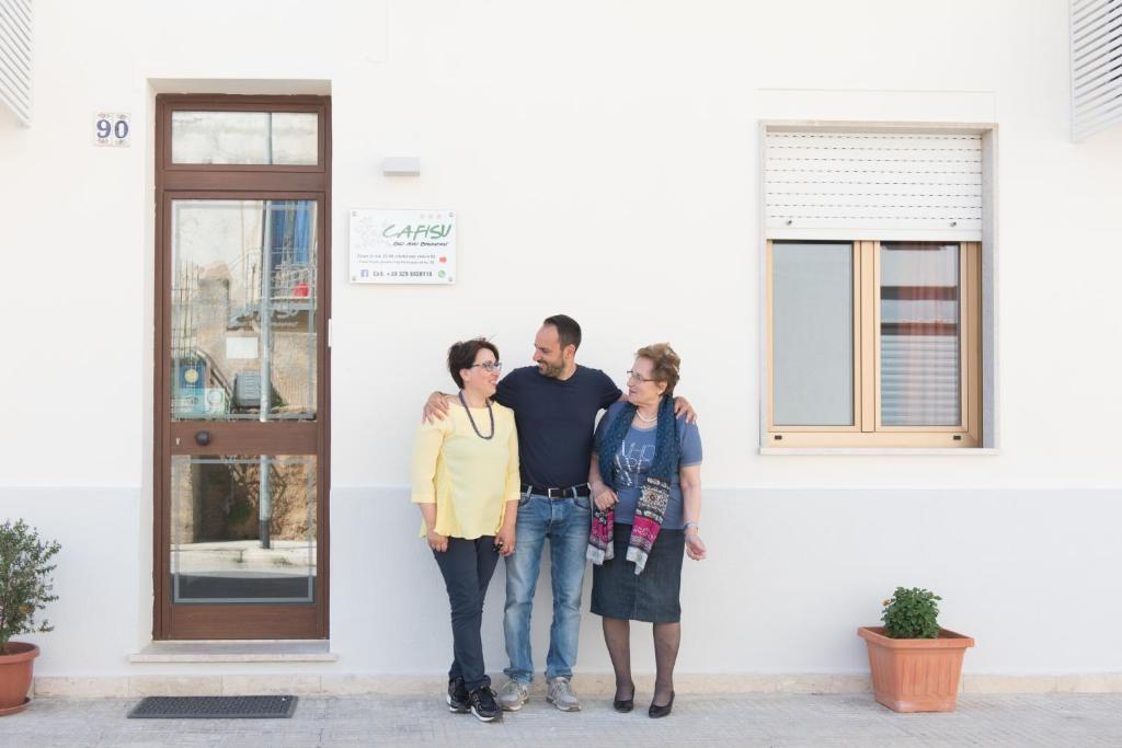 a group of three people standing in front of a building at B&B Cafisu in Paceco