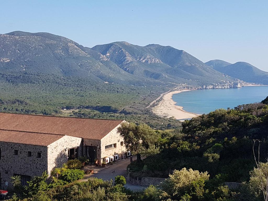 a building on a hill with a beach and mountains at Hotel Sardus Pater in Portixeddu