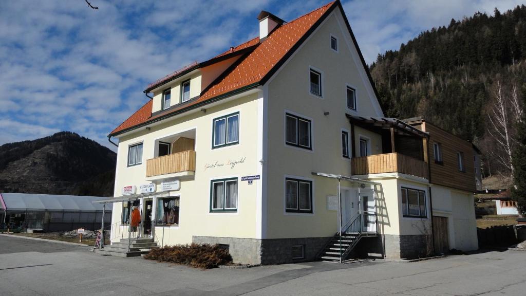 ein großes weißes Gebäude mit orangefarbenem Dach in der Unterkunft Gästehaus Leypold in Murau