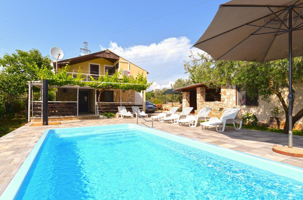 a pool with an umbrella and a house at House 1012 in Fažana