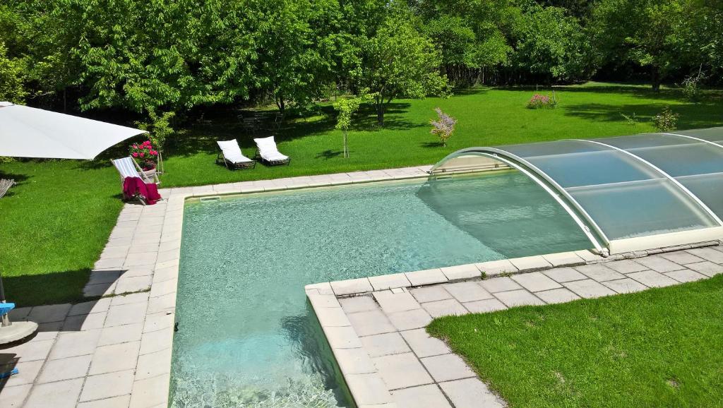 uma piscina num quintal com cadeiras e um guarda-sol em les trésors de malle mialle em Le Thor