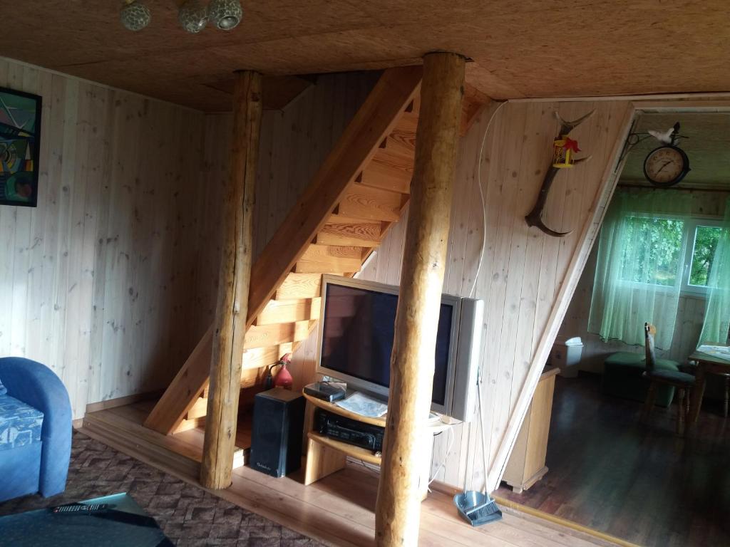a living room with a tv in a wooden house at Grāveri kempings in Usma