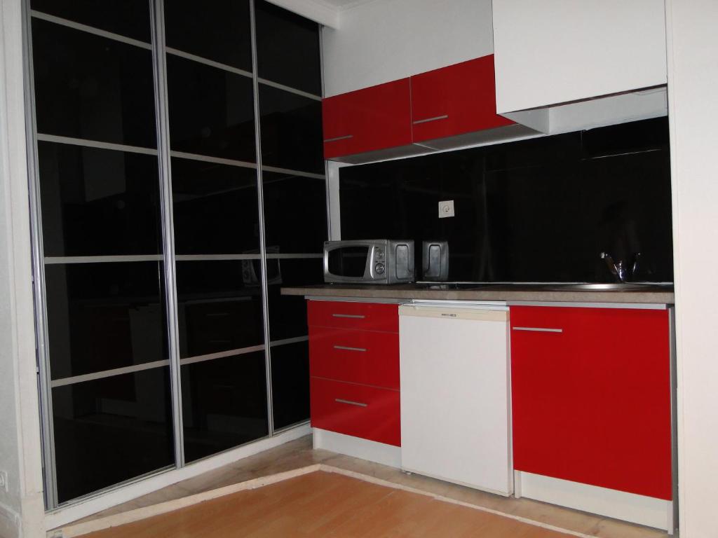 - une cuisine avec des placards rouges et blancs et un four micro-ondes dans l'établissement Appartement ENTRE TROCADERO et CHAMPS ELYSES, à Paris