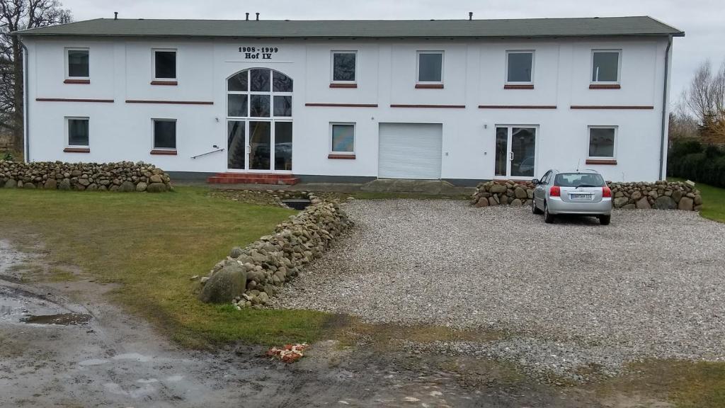 a car parked in front of a white building at Ferienwohnung Hahn in Börgerende-Rethwisch