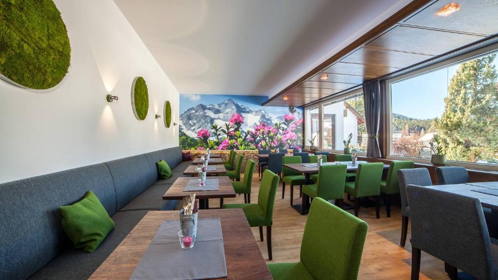 ゼーフェルト・イン・チロルにあるBoutique Hotel Olympiaのテーブルと緑の椅子、窓のあるレストラン
