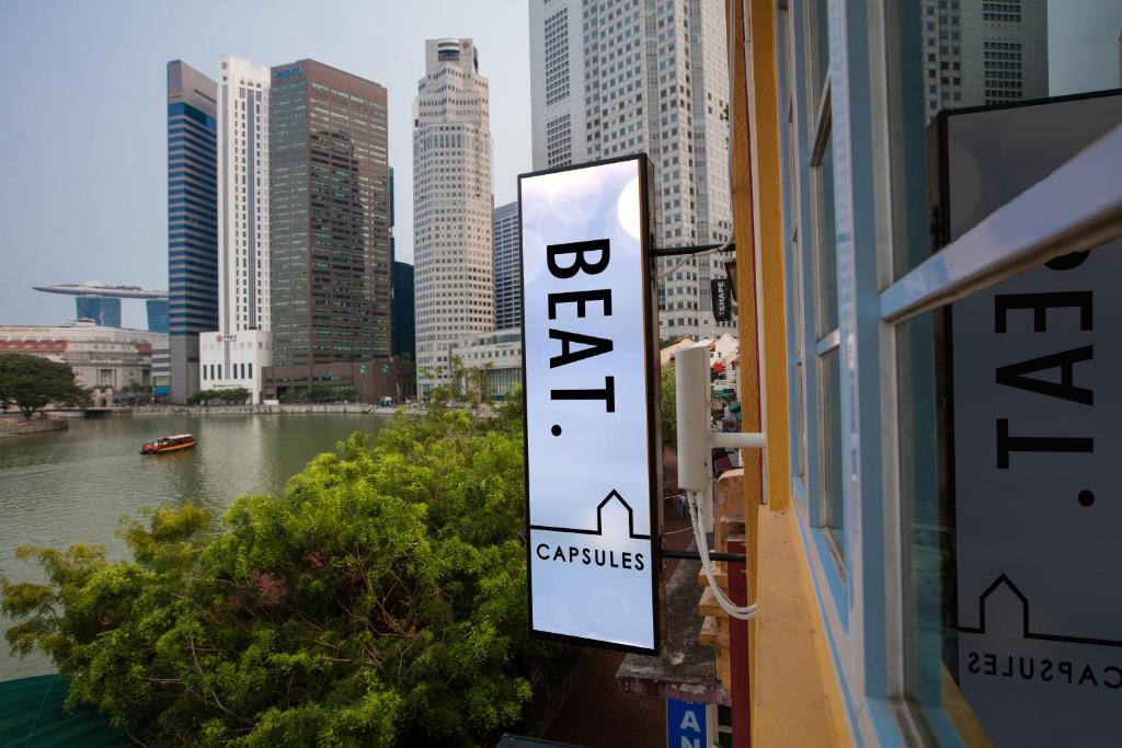 a sign in a window with a view of a city at BEAT. Capsule Hostel @ Boat Quay in Singapore