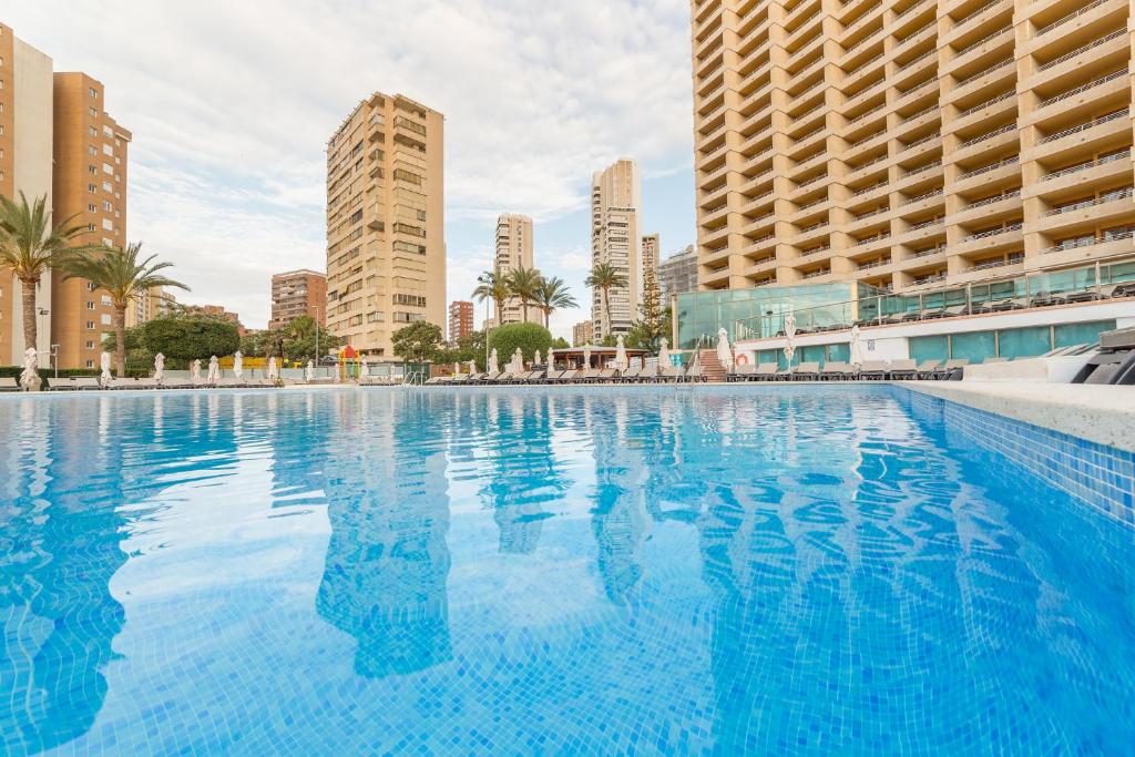 a large swimming pool in a city with tall buildings at Sandos Benidorm Suites in Benidorm