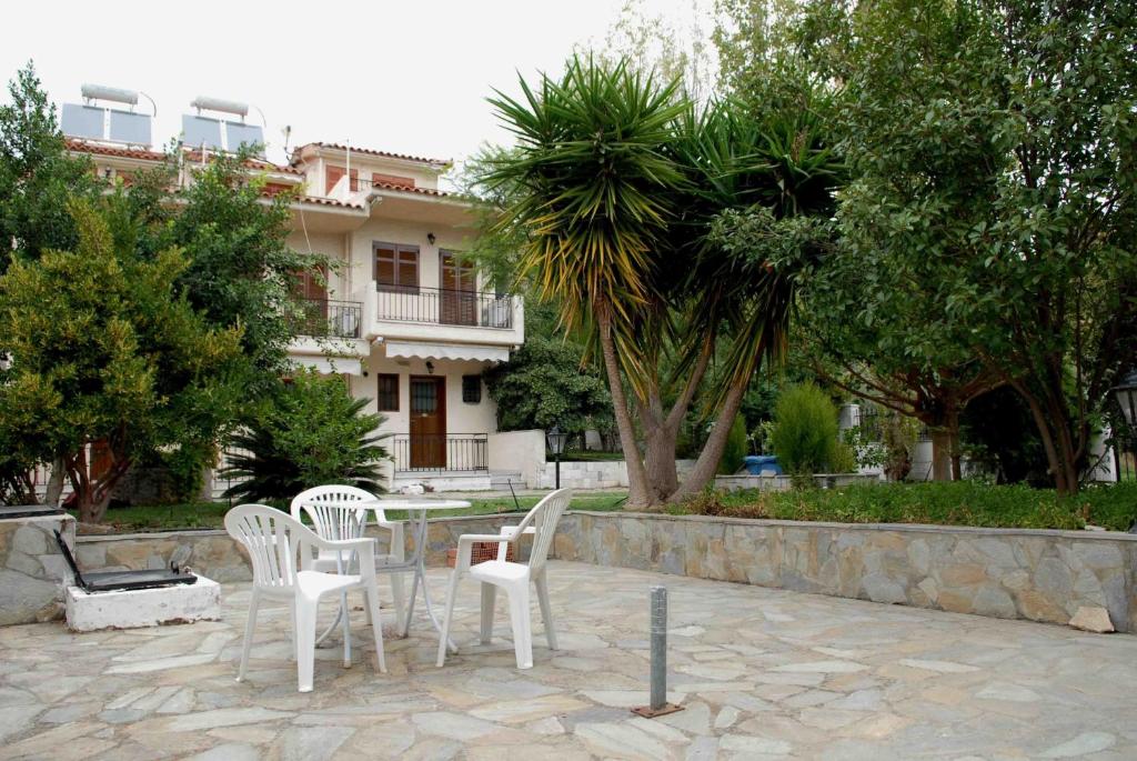 un patio con sillas blancas y una mesa frente a un edificio en Stathopoulos Apartments, en Sampatiki