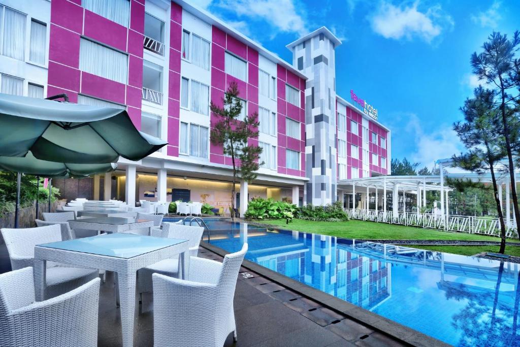 a hotel patio with a table and chairs and a pool at favehotel Cimanuk Garut in Garut