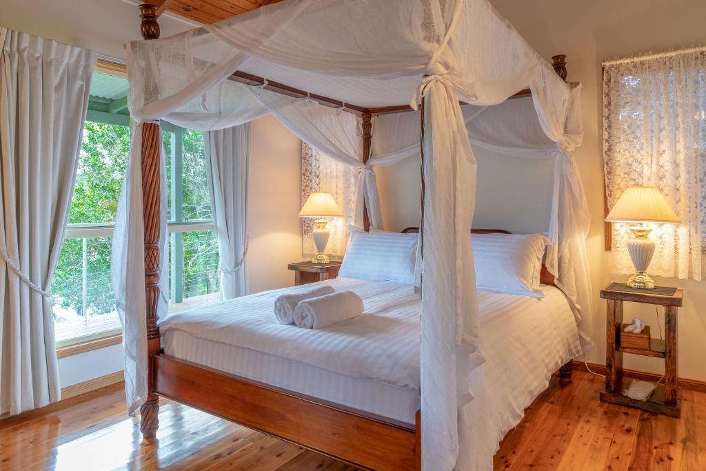 ein Schlafzimmer mit einem Himmelbett mit zwei Lampen in der Unterkunft Pencil Creek Cottages in Mapleton
