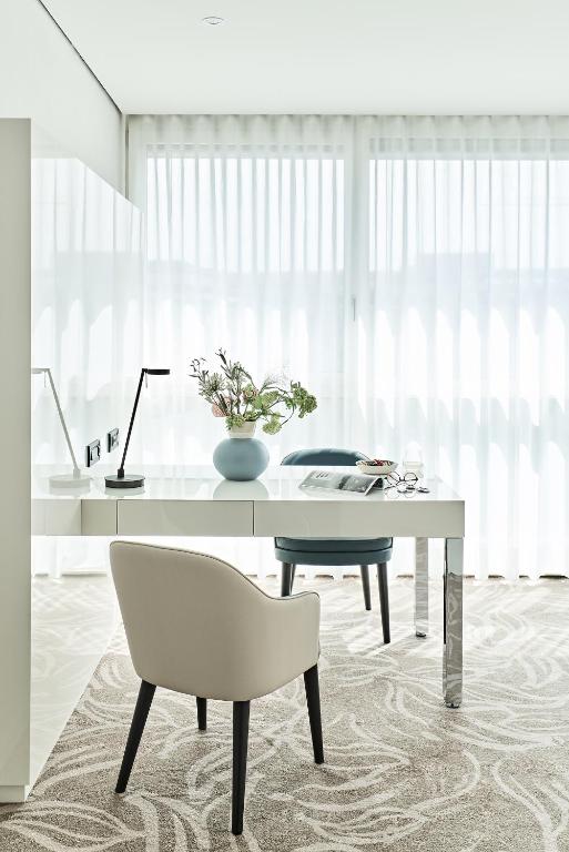 a white office with a desk and a chair at SIDE, Hamburg, a Member of Design Hotels in Hamburg