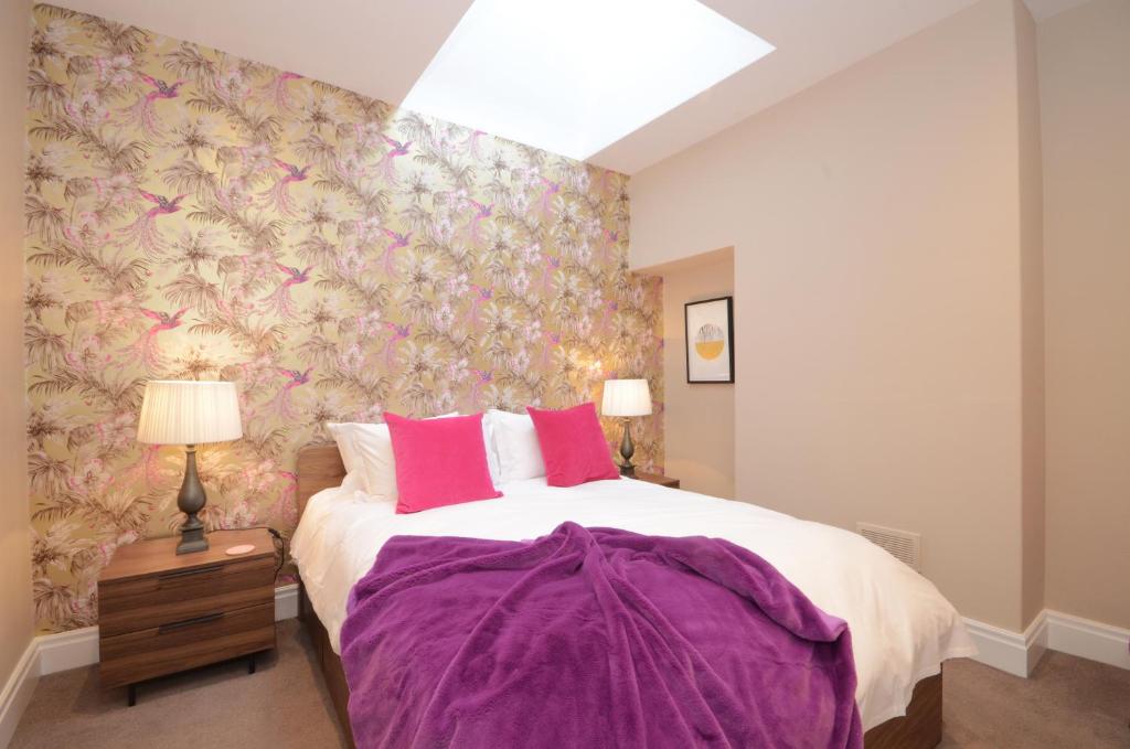 ヨークにあるLucy's Lodge- Most Stylish Apartment On Vibrant Bishy Roadのベッドルーム1室(ピンクの枕が付いた大型ベッド1台付)