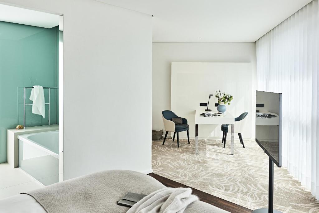 a white living room with a table and a chair at SIDE, Hamburg, a Member of Design Hotels in Hamburg