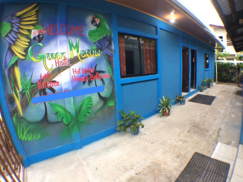 ein blaues Gebäude mit nebenstehenden Pflanzen in der Unterkunft Green Macaw Hostel in Tortuguero