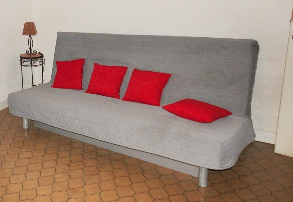Un sofá gris con cuatro almohadas rojas. en 2EGA37 Studio en centre-ville, en Collioure