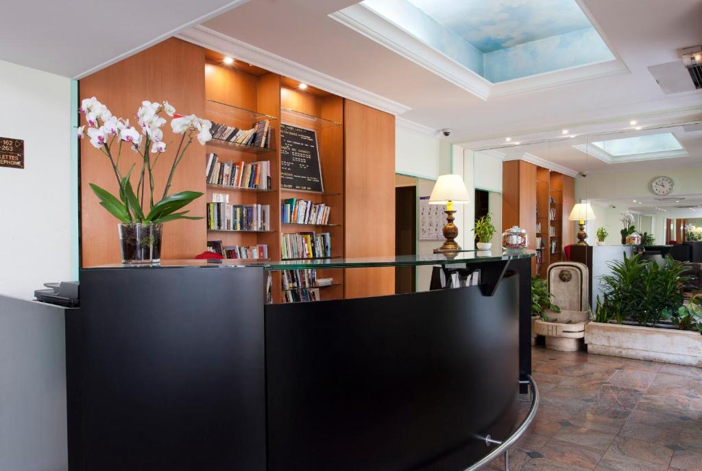 een lobby met een bibliotheek met een vaas met bloemen bij Home Latin in Parijs