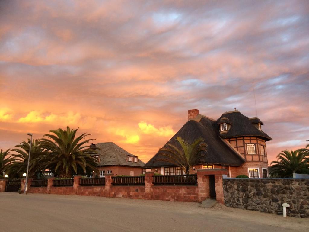 a house with a black roof with a sunset in the background at Villa Sohrada in Swakopmund