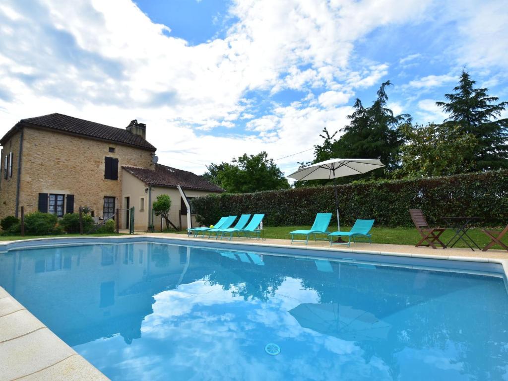 Villefranche-du-PérigordにあるModern holiday home in Besse with private poolのスイミングプール(青い椅子、パラソル付)