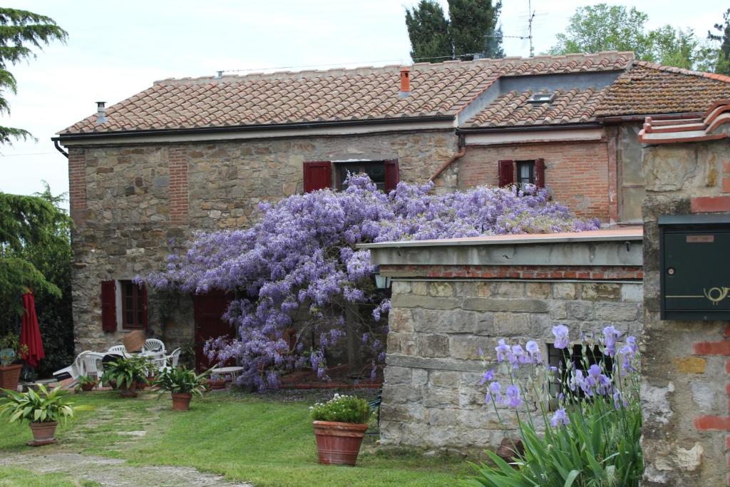 Una casa con flores púrpuras a un lado. en La Tinaia del Glicine, en Pratolino