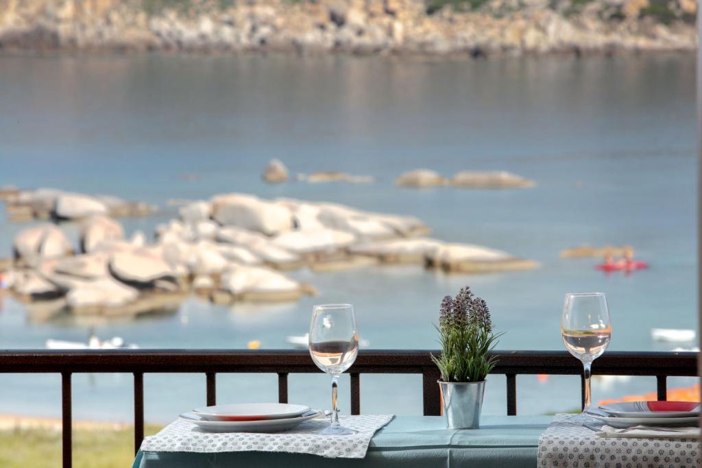 un tavolo con due bicchieri di vino sul balcone di Fronte Mare Capo Testa a Santa Teresa di Gallura