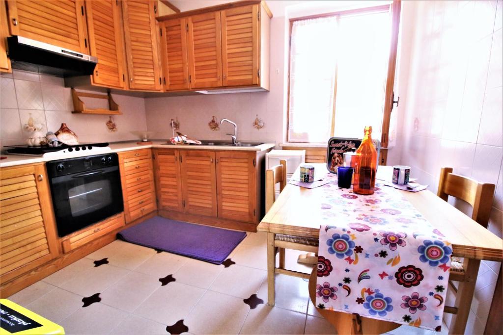 a kitchen with wooden cabinets and a table with a table cloth at holidaycasa Leone - Con posto auto a 200mt dal Mare in Sperlonga