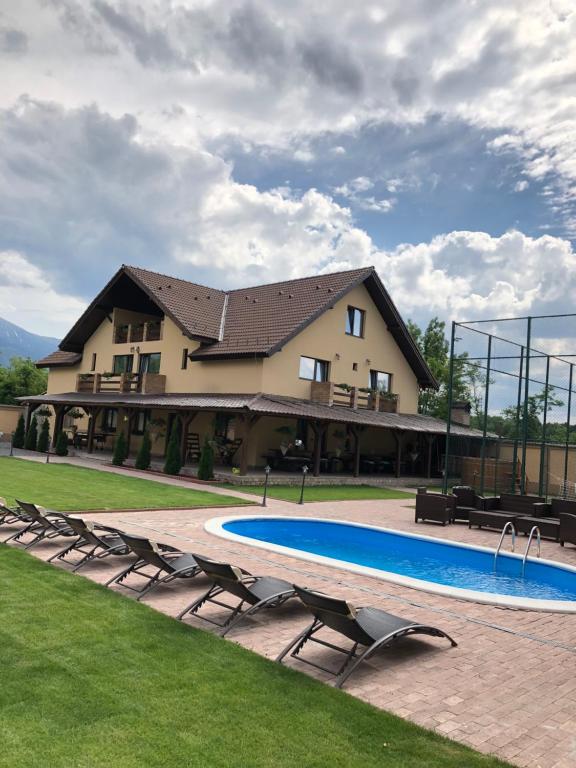 a large house with a swimming pool and chairs at Vila Smiley in Avrig