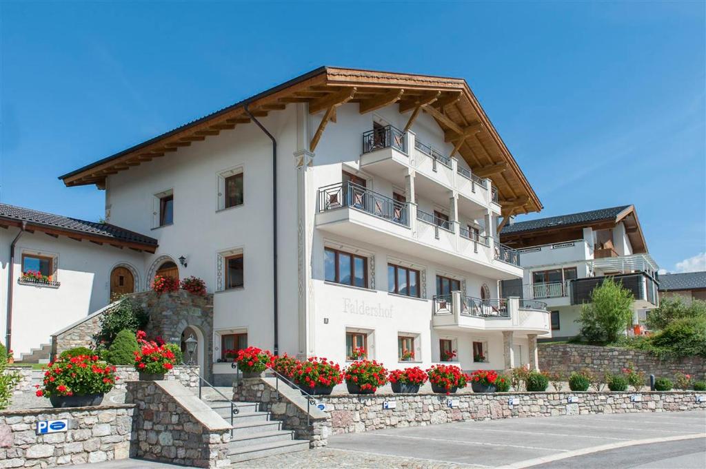ein großes weißes Gebäude mit Blumen davor in der Unterkunft Apart Faldershof in Fiss