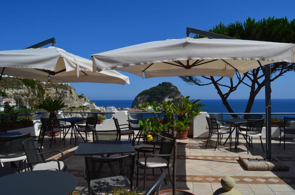 un patio con tavoli, sedie e ombrelloni di Hotel Casa Gerardo a Ischia
