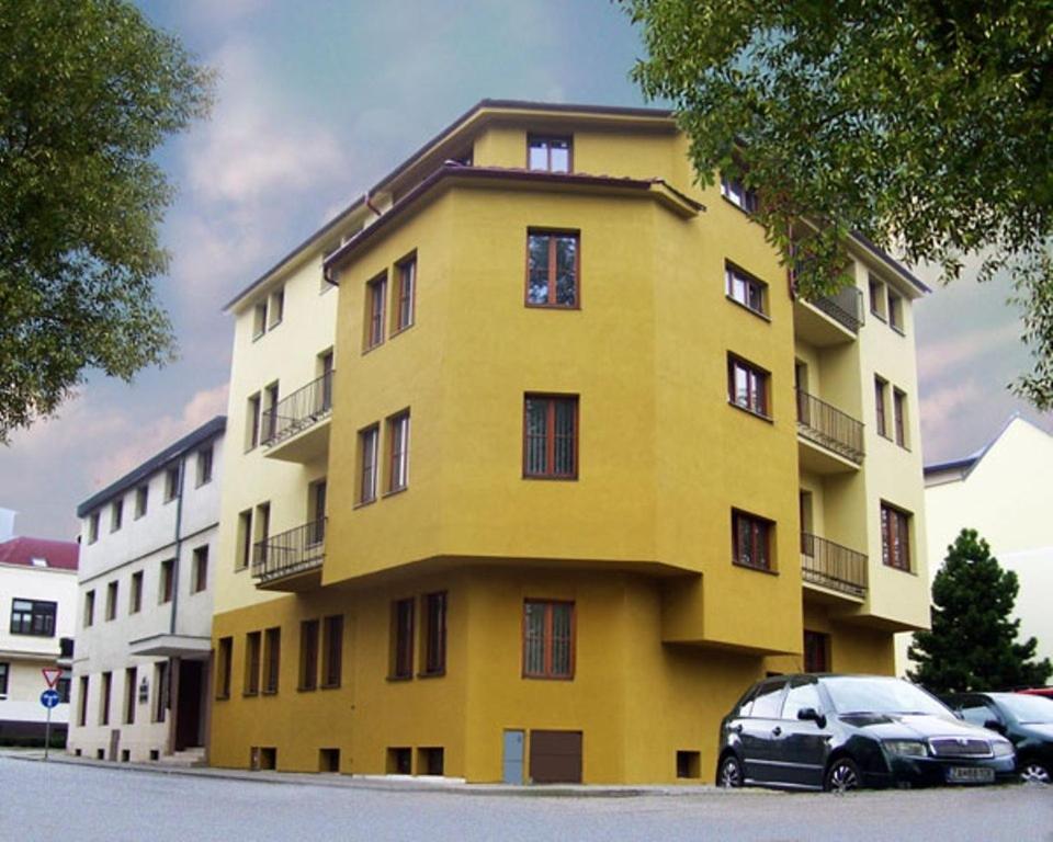 un edificio amarillo con coches estacionados frente a él en Hotel Slovan, en Žilina