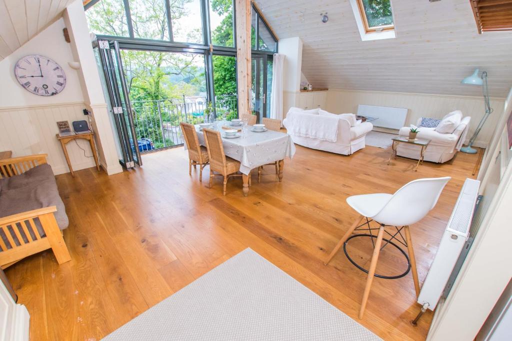 a living room with a table and chairs and a clock at The Garden Studios in Budleigh Salterton