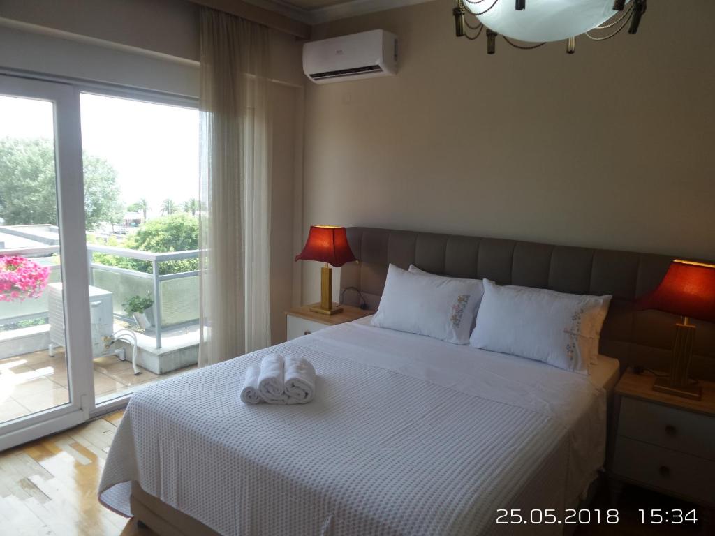 a bedroom with a white bed and a balcony at Kouros City Center in Kavala