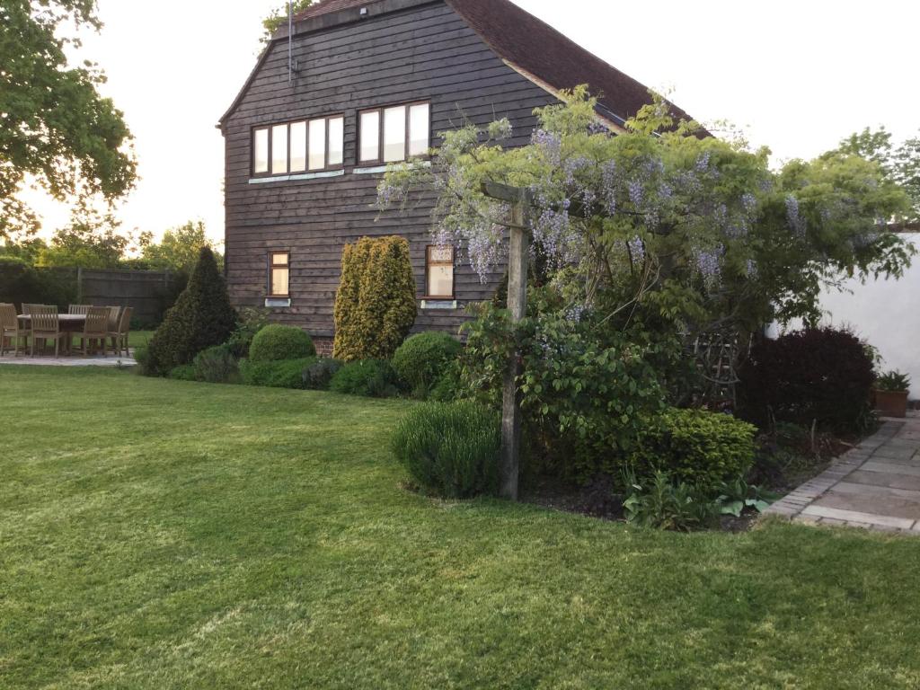 a house with a tree in front of a yard at Heartwood Barn in Ticehurst