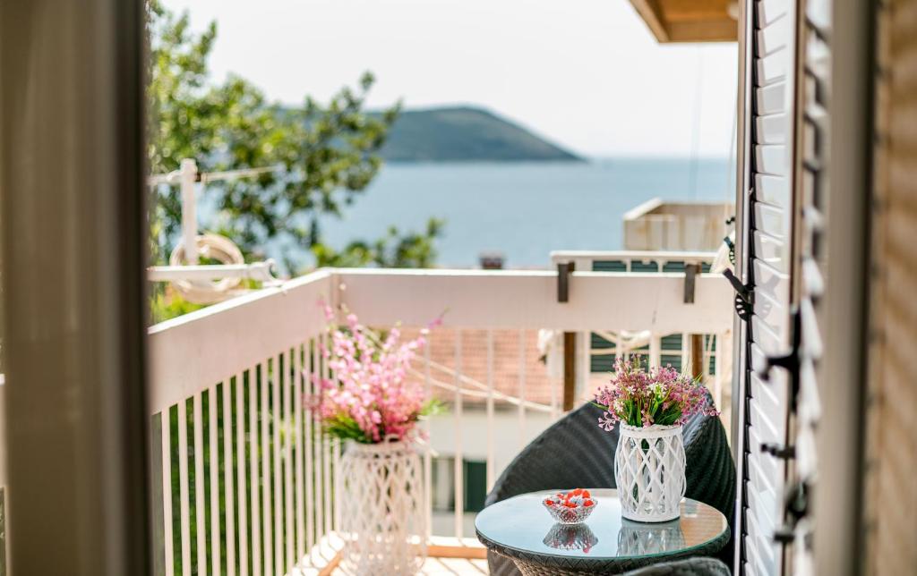 een tafel met twee vazen bloemen op een balkon bij Apartment Savin in Herceg-Novi