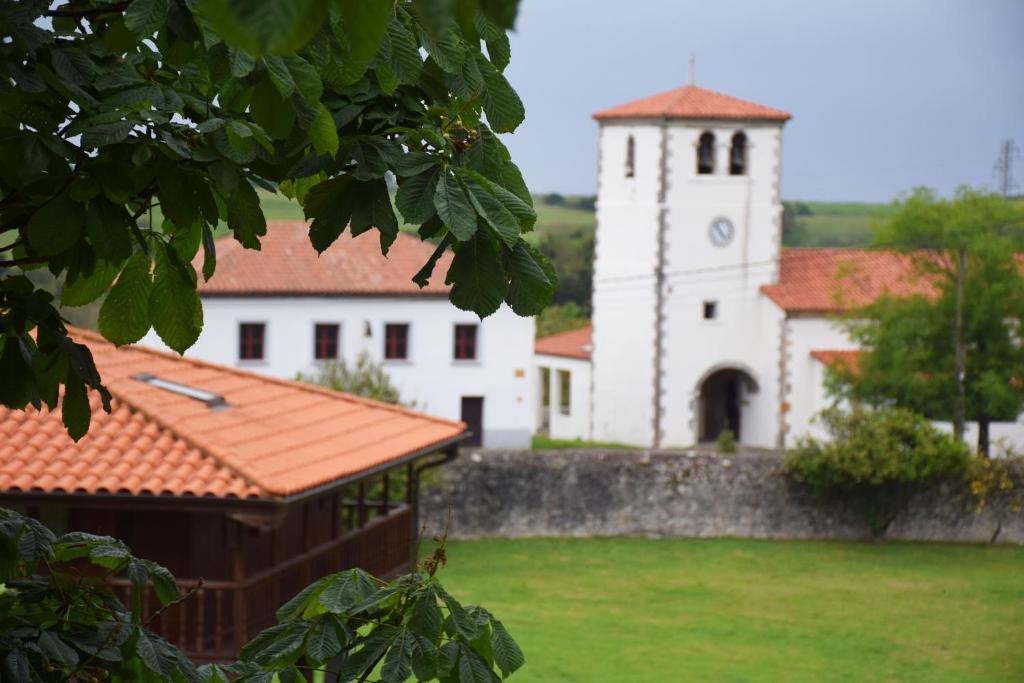 a white building with a clock tower in a field at Hotel Hontoria in Hontoria