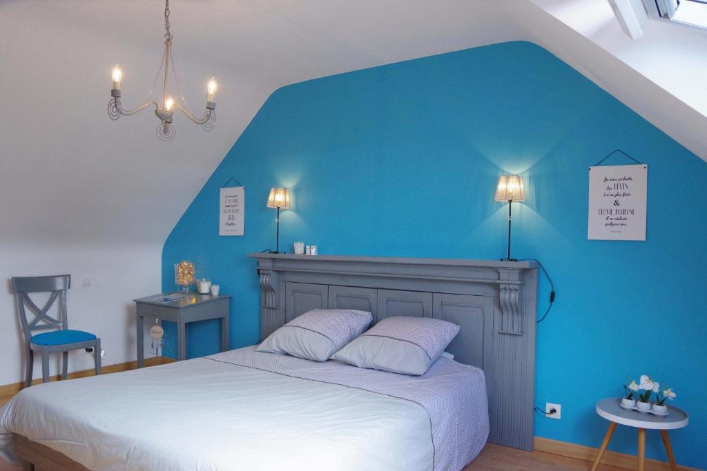 - une chambre bleue avec un lit et un mur bleu dans l'établissement Maison "Ouessant" Pays des Abers, à Plouguerneau
