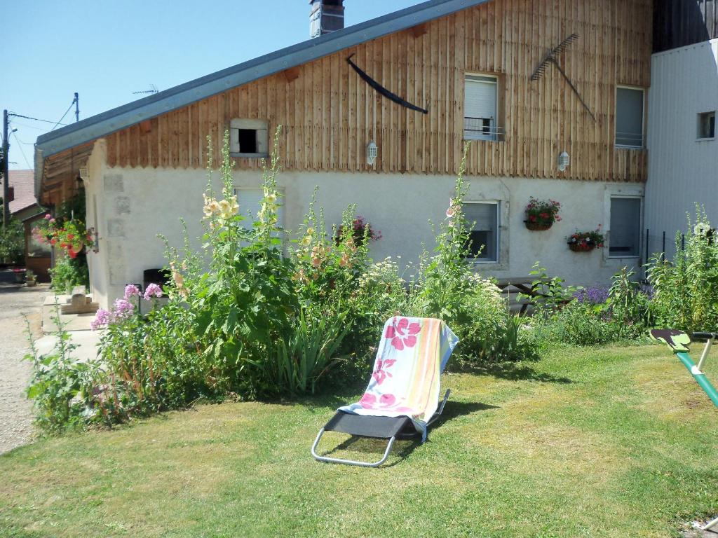 einem Stuhl im Gras vor einem Gebäude in der Unterkunft Gîte de la sauge in Mignovillard