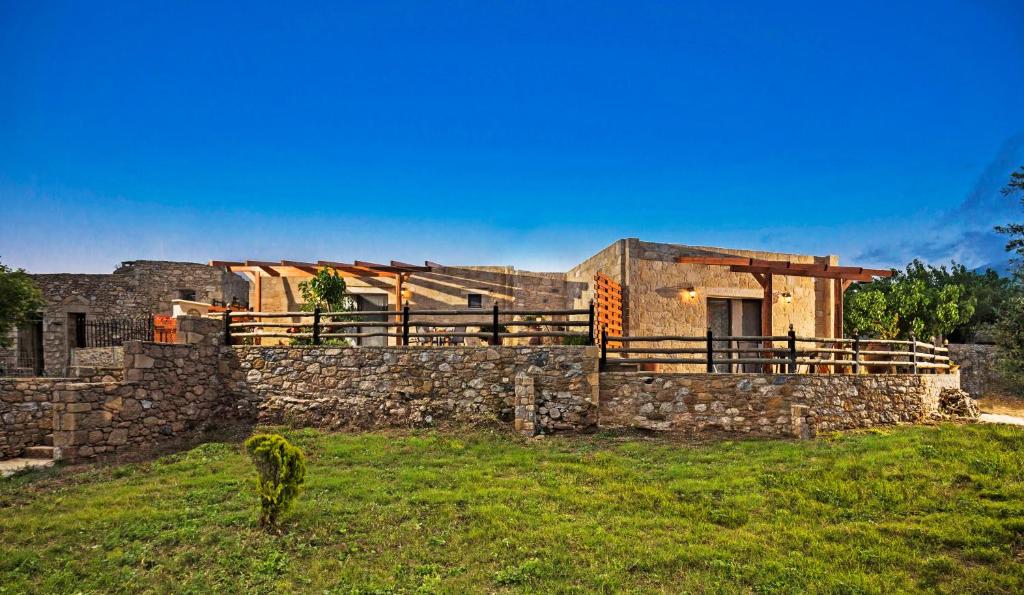 a house with a stone wall in a field at Petrakis Cretan Homes in Kissamos
