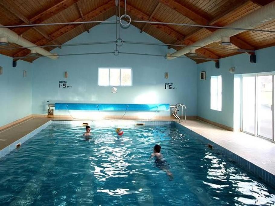 Dos personas están nadando en una piscina en Quilty Holiday Cottages - Type B, en Quilty