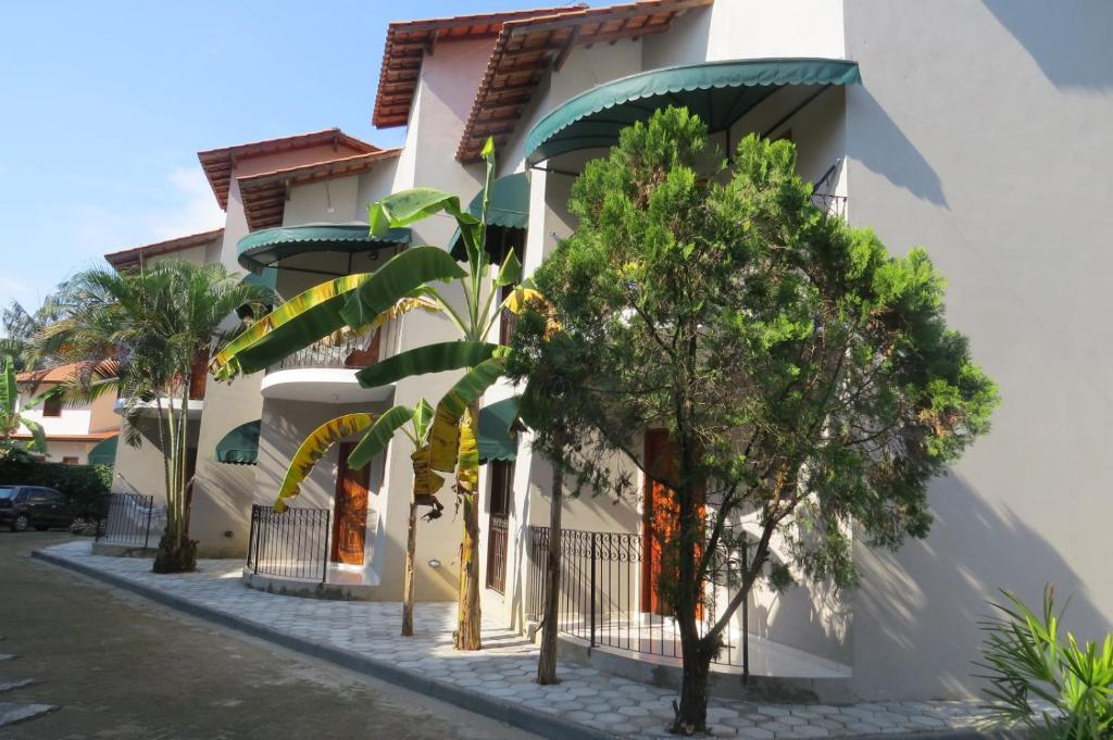 a white building with trees in front of it at Chalé no Caborê in Paraty