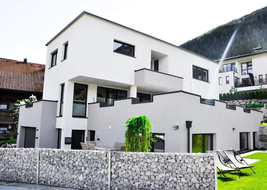 a white house with a stone fence at Appartement Alpenzauber in Arzl im Pitztal