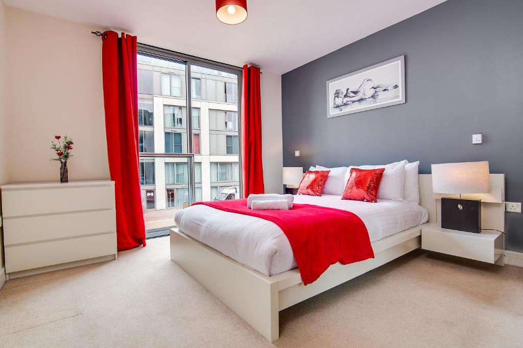 a bedroom with a bed with red curtains and a window at AJY Birmingham City Centre Viva Apartment in Birmingham