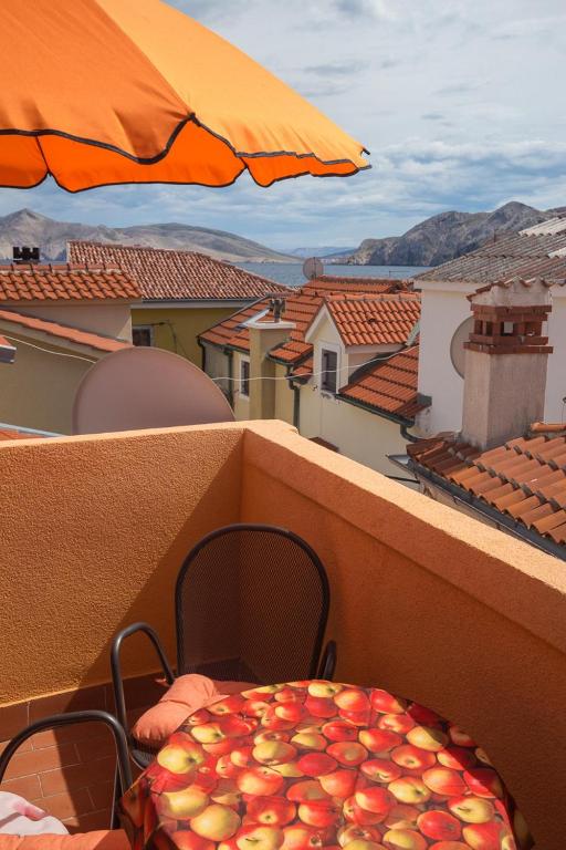 a table and chairs on a balcony with an umbrella at Apartment Neva with Terrace in Baška