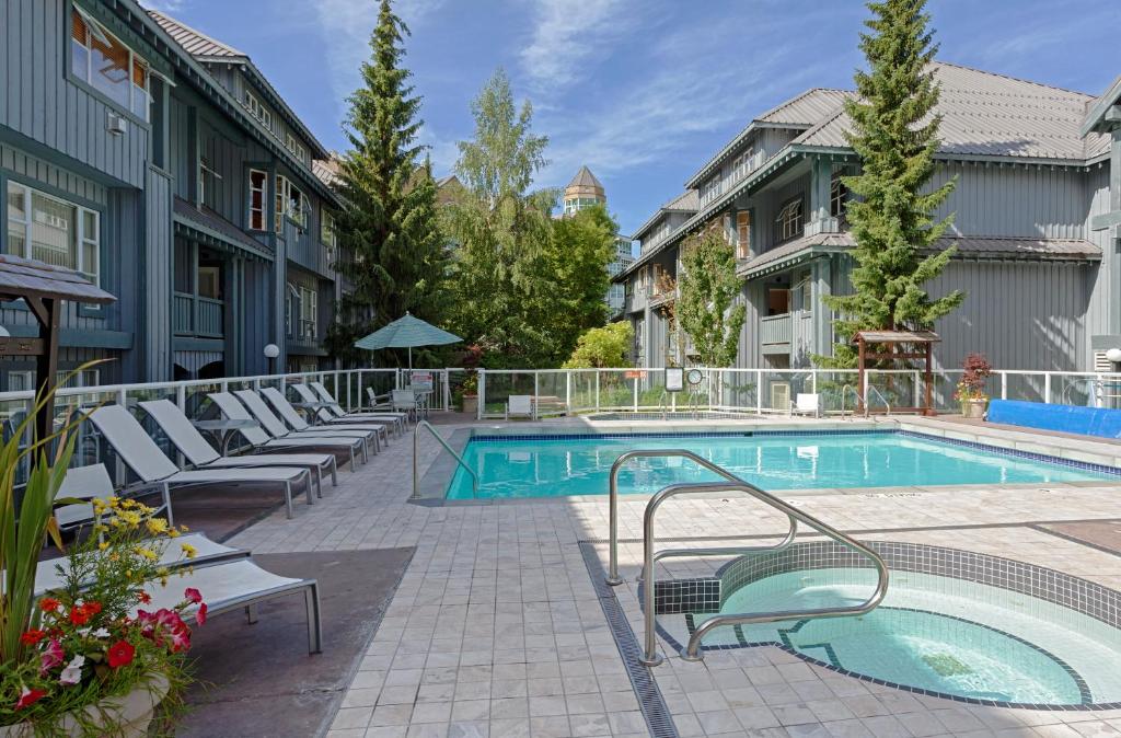 a pool at a hotel with lounge chairs around it at Glacier Lodge Resort in Whistler