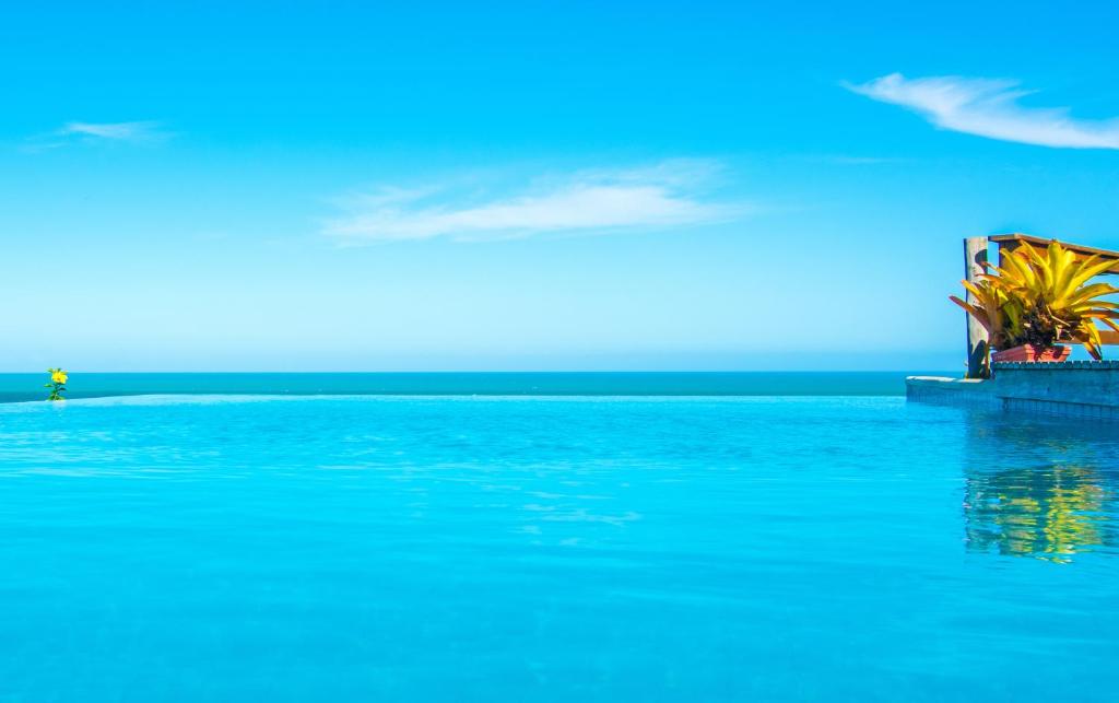 a person standing in the water near the ocean at Manacá Pousada Parque in Arraial d'Ajuda