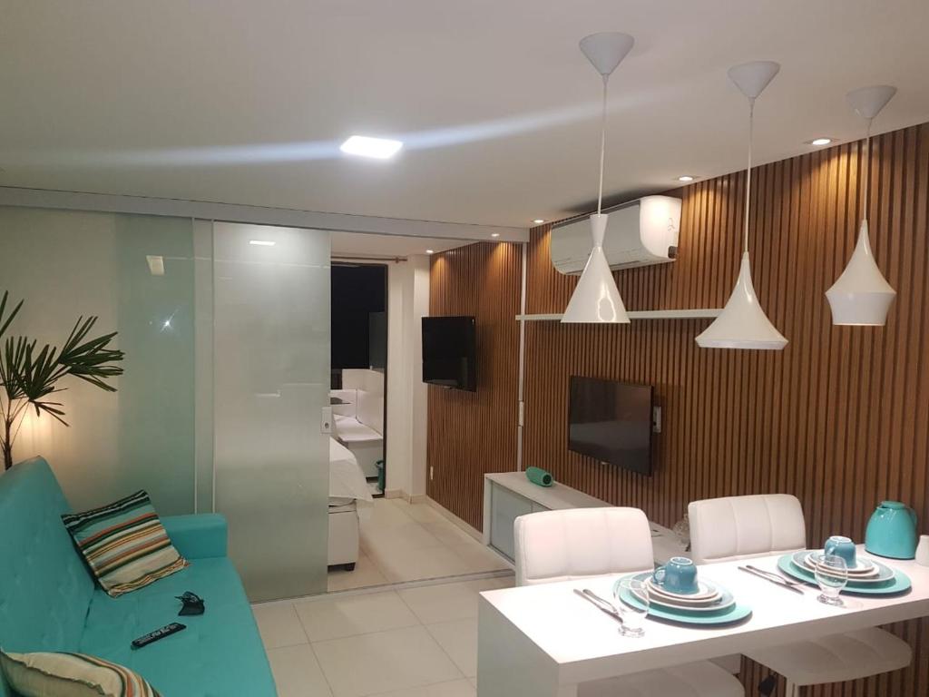 een woonkamer met een tafel en stoelen en een televisie bij Laguna Beach Flat in Porto De Galinhas
