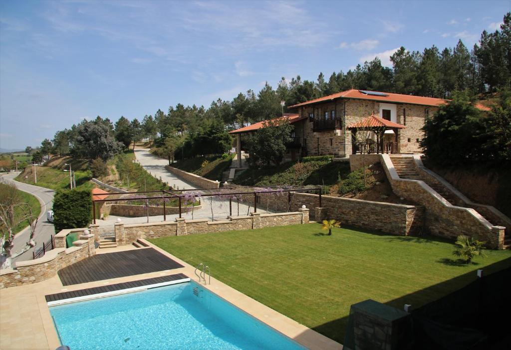 a house with a swimming pool in front of a yard at O Casario in Mirandela