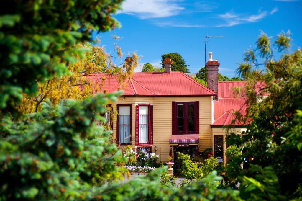 una casa amarilla con techo rojo en Central Springs Inn, en Daylesford