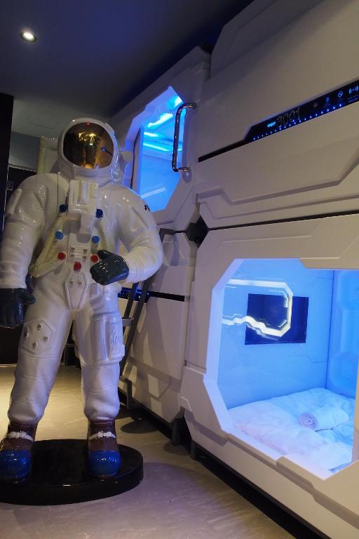 Um astronauta está ao lado de uma cama. em Space Hotel @ Chinatown Kuala Lumpur em Kuala Lumpur