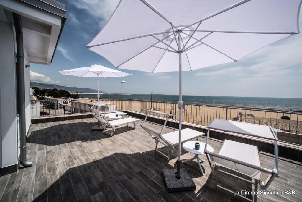 une terrasse avec un parasol blanc, des chaises et des tables dans l'établissement La Dimora Sipontina, à Manfredonia