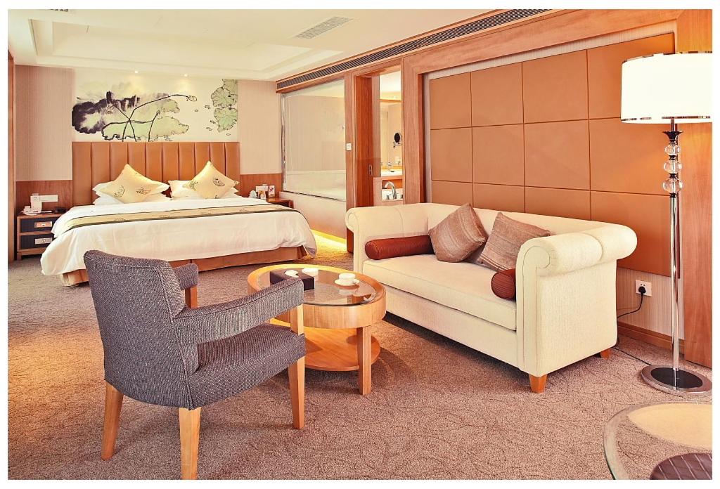 a hotel room with a bed and a couch and a chair at Jinling Plaza Changzhou in Changzhou